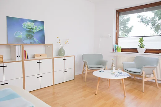 Gesprächsplatz im hellen Praxisraum mit zwei Sesseln, rundem Tisch und Fenster